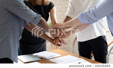 Diverse colleagues stack hands engaged in teambuilding activity Diverse colleagues stack hands engaged in teambuilding activity 69426869