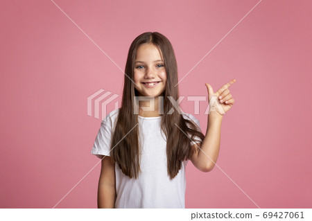 Kid with long hair presenting product. Happy little girl shows to empty space 69427061