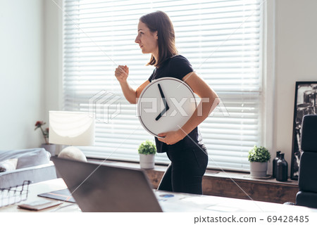 Woman with watch in her hand runs to or from work. 69428485