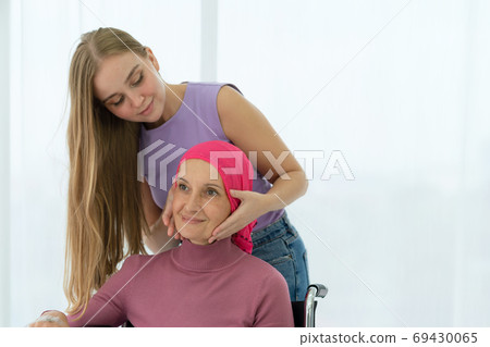 Young daughter embracing her sick mom who wearing headscarf on w 69430065
