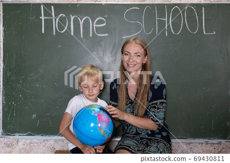 Mother is studying a world map on a globe with her son. 69430811