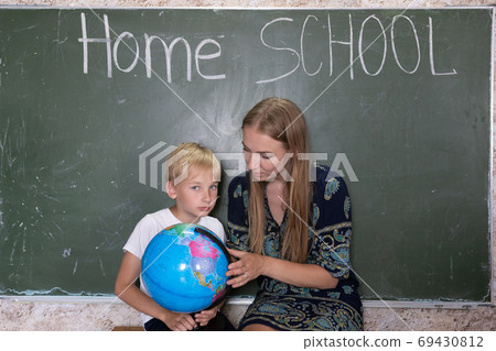 Mother is studying a world map on a globe with her son. 69430812