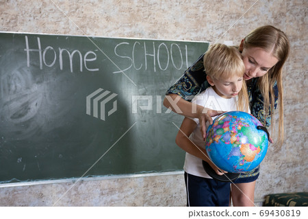 Mother is studying a world map on a globe with her son. 69430819