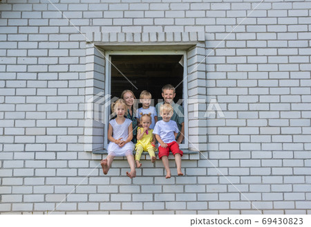 A large large family poses from the window of their home. A large large family poses from the window of their home. 69430823