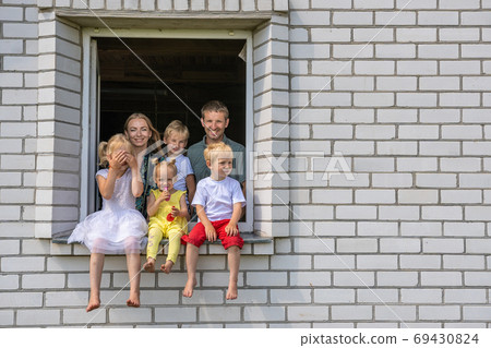 A large large family poses from the window of their home. A large large family poses from the window of their home. 69430824