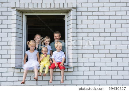 A large large family poses from the window of their home. A large large family poses from the window of their home. 69430827