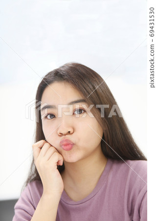 一個年輕的女人，盯著她的嘴唇銳化 69431530