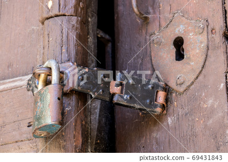 Close up of padlock and old hasp on an old wooden door. Locked old door with a cobweb. Close up of padlock and old hasp on an old wooden door. Locked old door with a cobweb. 69431843