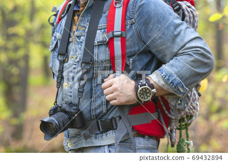 Close up photo of a human with backpack and a photocamera in a forest. 69432894