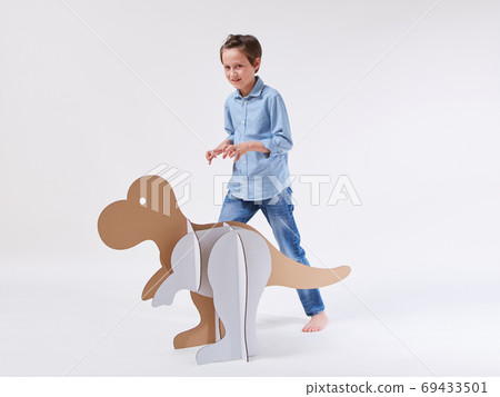 Little dreamer boy playing with a cardboard dinosaur Tyrannosaurus rex. Childhood. Fantasy, imagination. 69433501
