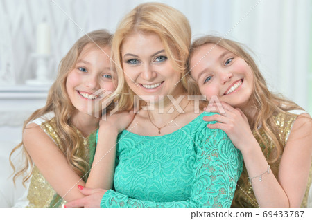 Cute smiling twin sisters hugging their mother 69433787