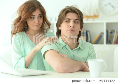 Portrait of young woman calming her husband 69434422