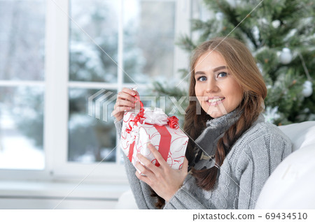 Portrait of smiling woman with Christmas gift Portrait of smiling woman with Christmas gift 69434510
