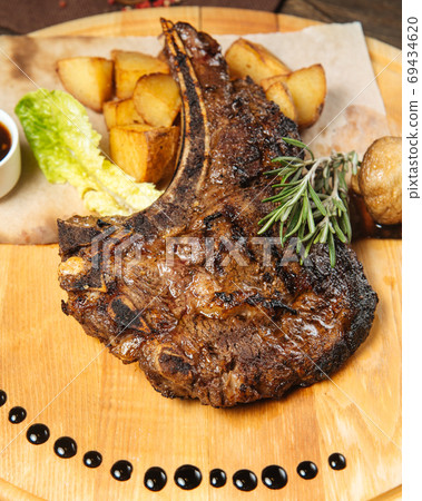 Closeup on cowboy beef steak on a wooden board 69434620
