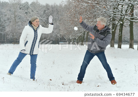 Happy senior couple at snowy winter park playing snowballs Happy senior couple at snowy winter park playing snowballs 69434677