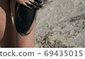 Healing black medical mud applies to leg and knee woman at the lake of salt water. Salty black dirt for people with health and skin problems. Relax at spa resort. Exfoliation scrub beauty treatment 69435015