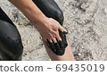 Healing black medical mud applies to leg and knee woman at the lake of salt water. Salty black dirt for people with health and skin problems. Relax at spa resort. Exfoliation scrub beauty treatment 69435019