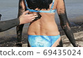 Healing black medical mud applies on back woman at the lake of salt water. Salty black dirt Is good for people with health and skin problems. Relax at spa resort. Exfoliation scrub beauty treatment 69435024