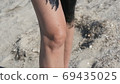Healing black medical mud applies to leg and knee woman at the lake of salt water. Salty black dirt for people with health and skin problems. Relax at spa resort. Exfoliation scrub beauty treatment 69435025