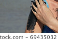 Healing black medical mud applies to arm shoulder woman at the lake of salt water. Salty black dirt for people with health and skin problems. Relax at spa resort. Exfoliation scrub beauty treatment 69435032