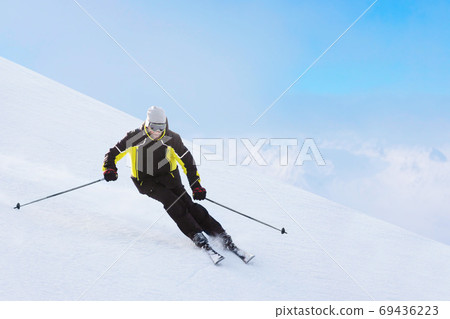Alpine skier on piste running downhill Alpine skier on piste running downhill 69436223