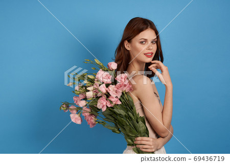 Beautiful woman with a bouquet of pink flowers on a blue background spring model Beautiful woman with a bouquet of pink flowers on a blue background spring model 69436719