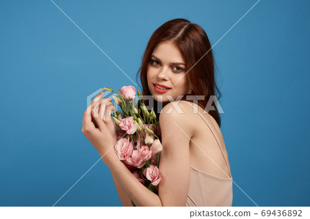 Beautiful woman with a bouquet of pink flowers on a blue background spring model Beautiful woman with a bouquet of pink flowers on a blue background spring model 69436892