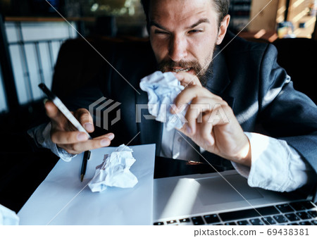 business man sitting at table in front of laptop crumpled paper lifestyle executive job technology 69438381