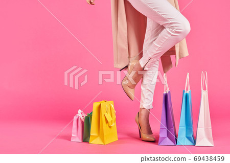shopping bags female feet in shoes Shopaholic pink background shopping bags female feet in shoes Shopaholic pink background 69438459