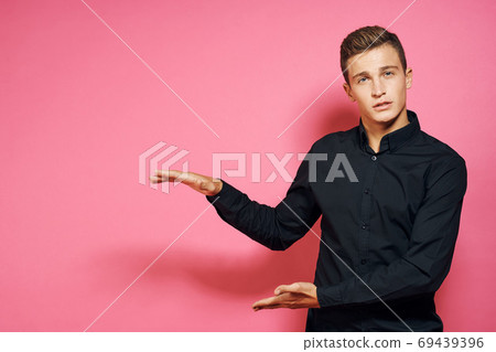 Man in black shirt gestures with hands lifestyle pink isolated background 69439396