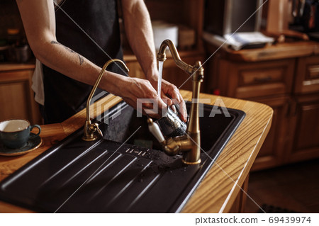 guy is washing the dishes in the kitchen with modern interior guy is washing the dishes in the kitchen with modern interior 69439974