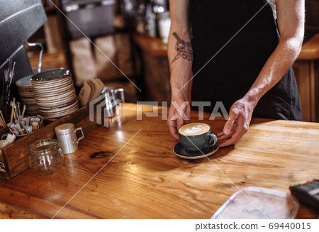 a man is serving latte on a wooden table a man is serving latte on a wooden table 69440015