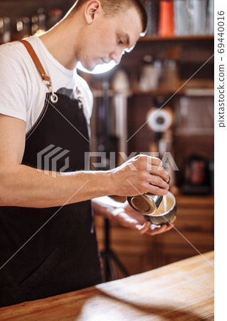 a coffeehouse employee is preparing espresso-based coffee drink 69440016