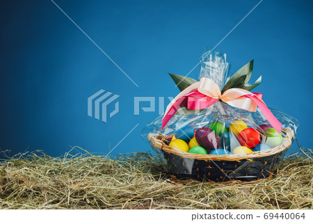 Easter gift basket with multicolor eggs, blue background 69440064
