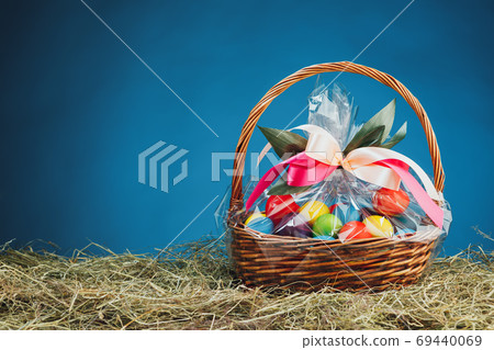Easter gift basket with multicolor eggs, blue background Easter gift basket with multicolor eggs, blue background 69440069