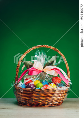 Easter gift basket with multicolor eggs, green background Easter gift basket with multicolor eggs, green background 69440072