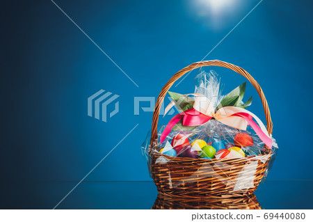 Easter gift basket with multicolor eggs, blue background Easter gift basket with multicolor eggs, blue background 69440080