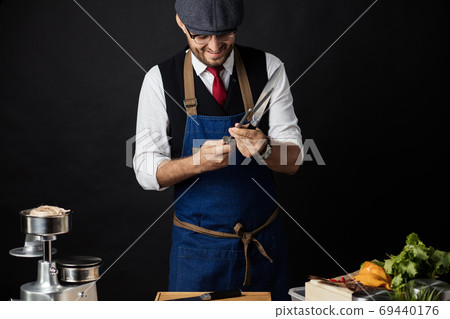 Midsection of male chef sharpening knife in commercial kitchen Midsection of male chef sharpening knife in commercial kitchen 69440176