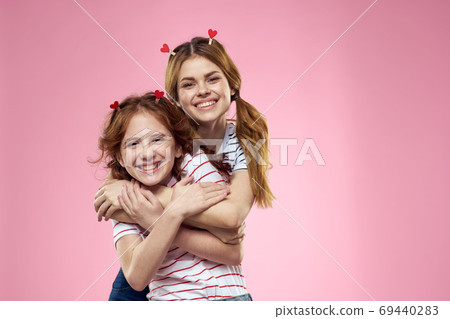 Cheerful mom and daughter joy lifestyle studio pink background family Cheerful mom and daughter joy lifestyle studio pink background family 69440283