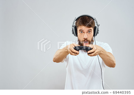 Man in headphones with gamepad playing hobby entertainment lifestyle light background 69440395