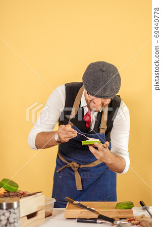 Cook preparing burger adding the sauce on green bun. Cook preparing burger adding the sauce on green bun. 69440778