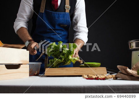Cook adding lettuce on burger. Preparing burger. Cook adding lettuce on burger. Preparing burger. 69440899