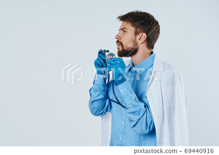man in medical gown laboratory assistant with liquid in flask and stethoscope doctor chemical reaction light background 69440916
