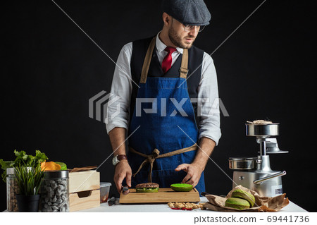 Man cooking green burger with beef, salad and vegetables. 69441736
