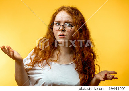 Isolated shot of young funny redhead female stares at camera with shoked expression 69441901