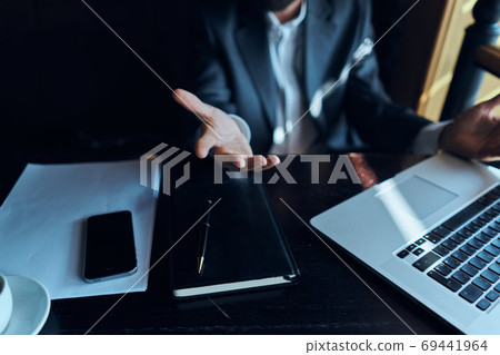 A business man in a suit is sitting in a cafe or with a laptop the work is an official A business man in a suit is sitting in a cafe or with a laptop the work is an official 69441964