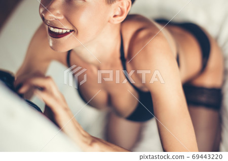 Attractive woman unzipping man jeans over black background Attractive woman unzipping man jeans over black background 69443220