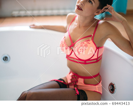 Seductive woman in red lingerie taking bath in jacuzzi at spa centre Seductive woman in red lingerie taking bath in jacuzzi at spa centre 69443413