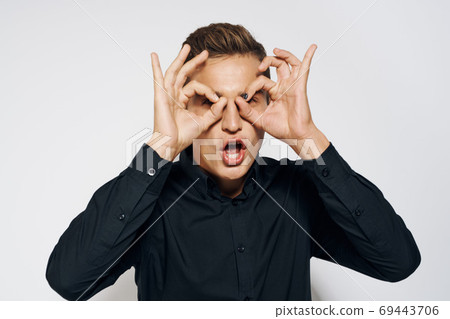 Man in black shirt lifestyle emotions modern style cropped view light background Man in black shirt lifestyle emotions modern style cropped view light background 69443706