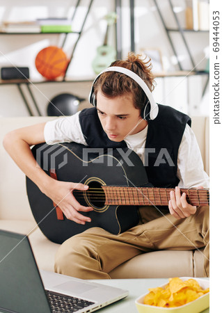 Boy following chords on laptop Boy following chords on laptop 69444053